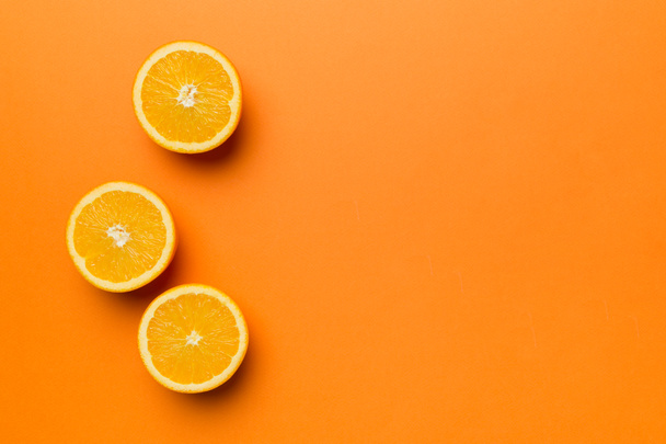 新鮮なフルーツオレンジのスライスを着色された背景に。最上階だ。コピースペース。創造的な夏のコンセプト。コピースペースと最小限のフラットレイアウトで柑橘類の半分. - 写真・画像