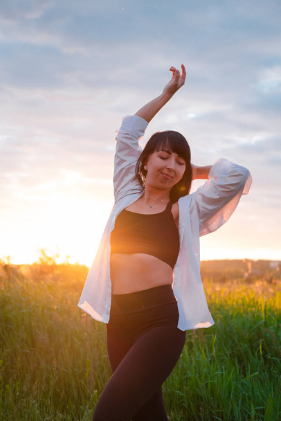 молодая женщина в Baldric на летнем поле на закате или восходе солнца. мирная спокойная женщина. модная одежда. - Фото, изображение