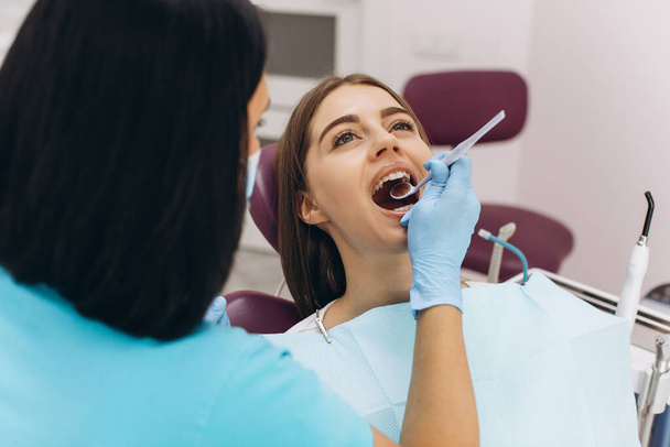 Une dentiste examine sa patiente dans une chaise dentaire. - Photo, image