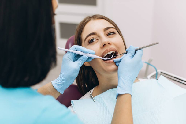 Жінка-стоматолог оглядає свого пацієнта в стоматологічному кріслі
. - Фото, зображення