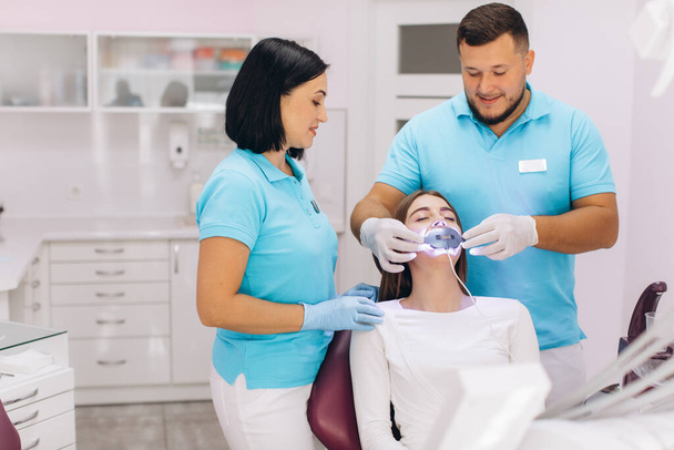 Les dentistes donnent à la fille le blanchiment des dents aux ultraviolets dans une clinique dentaire - Photo, image