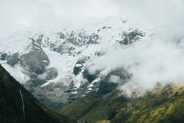 Ευρεία γωνία ενός χιονισμένου ορεινού τοπίου με καταρράκτη και μερικά σύννεφα. Οριζόντια. με χώρο αντιγραφής. - Φωτογραφία, εικόνα