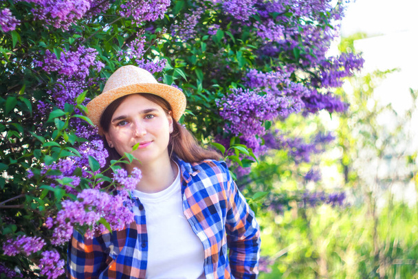 Spring allergy. Defocus beautiful young woman near blooming spring tree. Bush lilac flowers. Youth, love, fashion, romantic, lifestyle concept. Girl in hat nature background. Out of focus. - Photo, Image