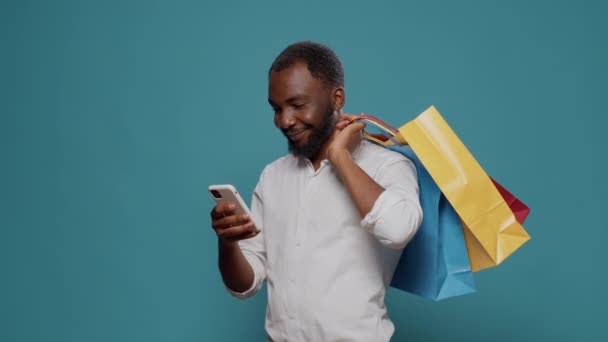 Modern bir insan alışveriş torbaları taşır ve akıllı telefon kullanır. - Video, Çekim