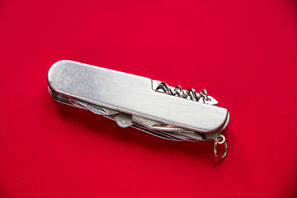 Metallic swiss knife isolated on red background - Φωτογραφία, εικόνα