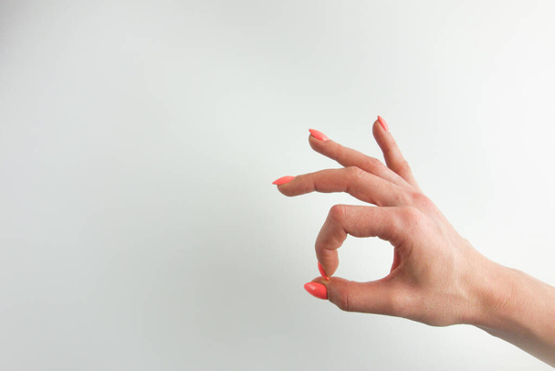 Main de femme avec ongles orange pastel faisant un geste correct. Fond blanc, espace de copie pour votre conception - Photo, image