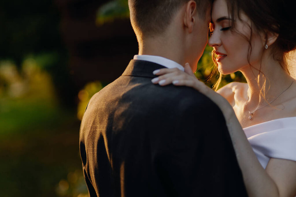  Beautiful newlyweds are hugging in the park at sunset. Close-up. Place for your text. High quality photo - Foto, Imagem