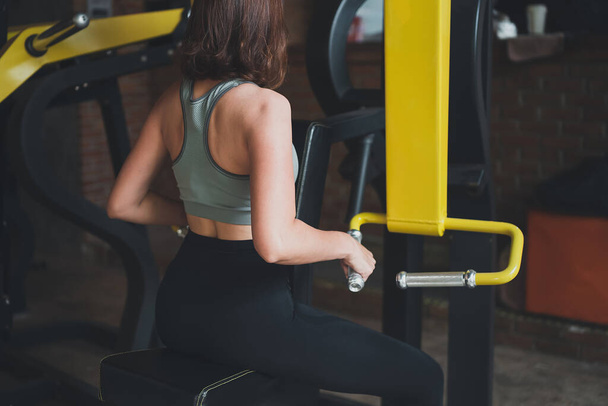 Ασιατικές αθλητικές γυναίκες προπόνηση dumbbell προπόνηση μηχάνημα κατάρτισης στο γυμναστήριο. προπόνηση κορίτσι αθλητής ισχυρή και καλή υγεία και δύναμη - Φωτογραφία, εικόνα