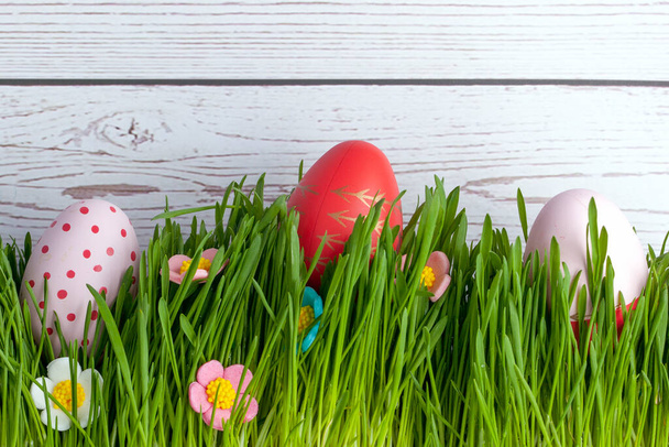 Easter composition with eggs, rabbit , sweet flowers  and grass, on the wooden background - Photo, Image