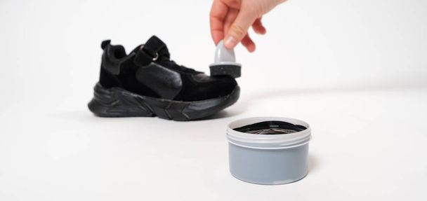 Uma pessoa aplica creme de tinta esponja às migalhas pretas da criança. Cuidados para couro de crianças e sapatos de camurça. - Foto, Imagem