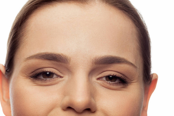 Cropped close-up image of female beautiful brown eyes looking at camera isolated over white studio background. Smiling - Foto, afbeelding