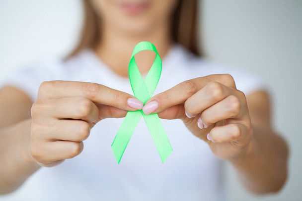 Üniformalı doktor Lyme hastalığının sembolü olarak yeşil bir kurdele tutuyor. - Fotoğraf, Görsel