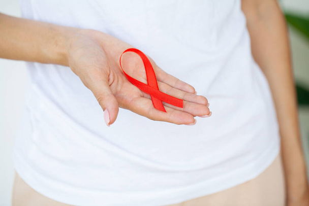 Mujer sosteniendo la cinta roja VIH, cinta de sensibilización del día mundial del SIDA. - Foto, imagen