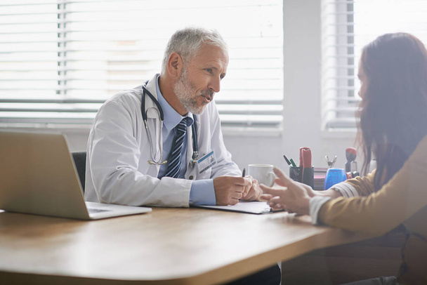 Dedicated to the health of his patients. Shot of a doctor meeting with his patient. - Foto, imagen