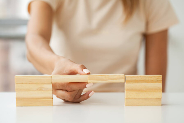 Kobiecy ręka robi drewniane kostki na białym stole - Zdjęcie, obraz