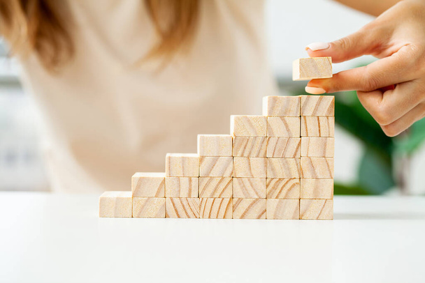 Stapeln von Holzwürfeln von Hand als Treppenstufen-Form - Foto, Bild