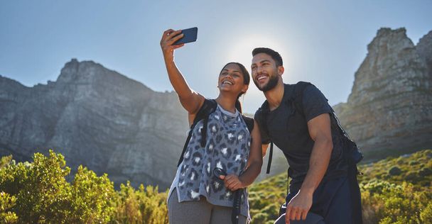 Genießen Sie all das Vitamin D auf die beste Weise. Aufnahme eines jungen Paares beim Fotografieren während einer Wanderung in einem Gebirgszug im Freien. - Foto, Bild