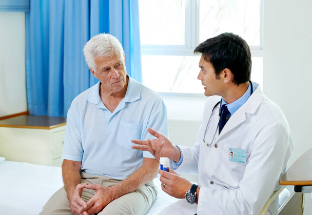 Gli effetti indesiderati sono rari. Una foto di un bel giovane dottore che spiega le medicine ad un paziente anziano. - Foto, immagini