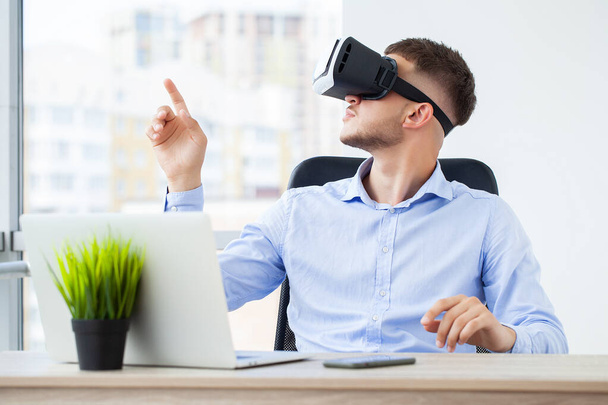 Man in office clothes and virtual reality glasses touching air. - Photo, image