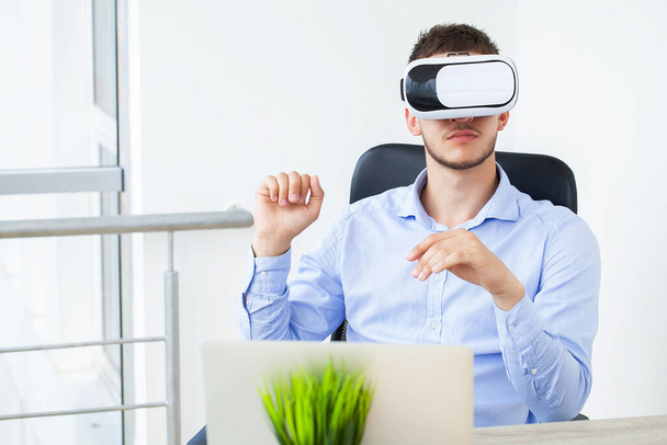 Άνδρας με ρούχα γραφείου και γυαλιά εικονικής πραγματικότητας αγγίζοντας τον αέρα. - Φωτογραφία, εικόνα