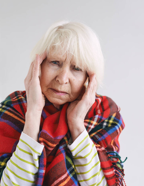 starší žena s bolestí hlavy v kostkovaných kostkách. Zdravotní péče, zralý věk, koncepce onemocnění - Fotografie, Obrázek