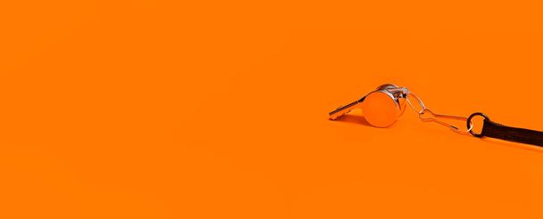 Sports whistle on orange background. Concept - sport competition, referee, statistics, challenge. Basketball, handball, futsal, volleyball, soccer, baseball, football and hockey referee whistle - Photo, Image