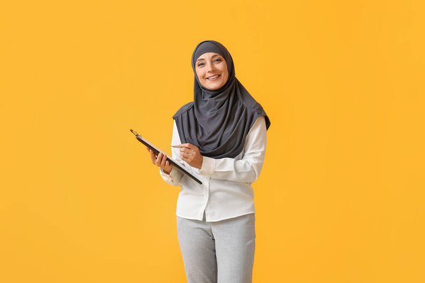 Porträt einer muslimischen Sekretärin mit Klemmbrett auf farbigem Hintergrund - Foto, Bild
