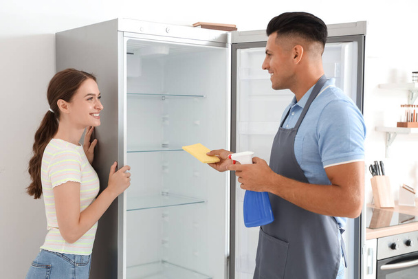 Молода пара прибирає холодильник на кухні
 - Фото, зображення