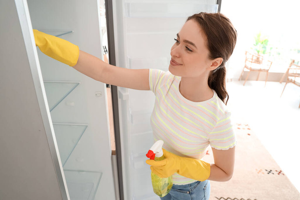 Nuori nainen puhdistaa jääkaappi keittiössä - Valokuva, kuva
