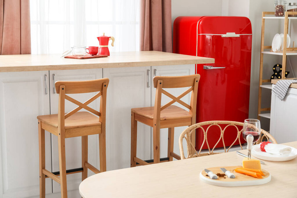 Interior de cocina ligera con nevera retro, mostradores blancos y sillas - Foto, Imagen