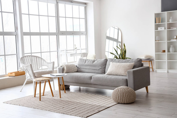 Интерьер стильной гостиной с удобным диваном, креслом и столом с ноутбуком - Фото, изображение