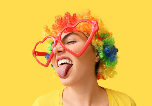 Funny young woman in disguise on yellow background. April fools' day celebration - Photo, image