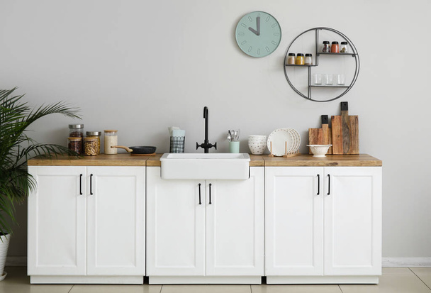 pulty s keramickým dřezem, kuchyňským nádobím a jídlem u světelné stěny - Fotografie, Obrázek