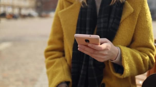 Primer plano de las manos de las mujeres utilizando un teléfono inteligente moderno en la calle de la ciudad de otoño.  - Metraje, vídeo