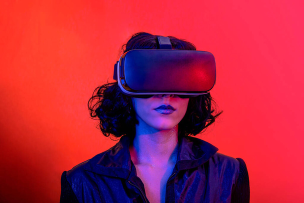 Die junge Frau benutzt das Virtual-Reality-Headset. Modernes Frauenporträt mit trendigem Look und hellen Farben. - Foto, Bild
