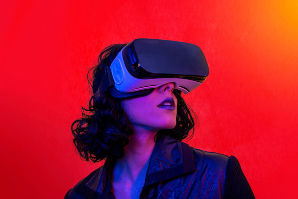 La joven está usando los auriculares de realidad virtual. Retrato de mujer moderna con aspecto moderno y colores brillantes. - Foto, Imagen