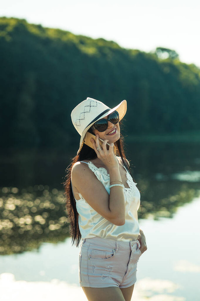 Cool girl talking on the phone by the river. - Photo, image