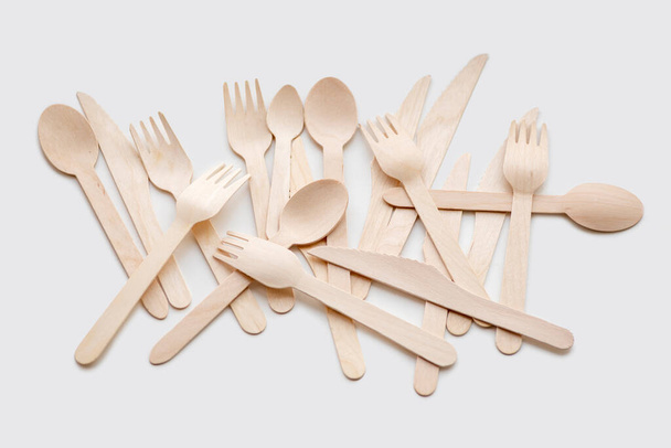 Shot of wooden eco-friendly cutlery lying chaotically on a white background. Ecology concept - Photo, Image