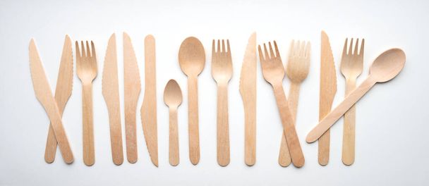 Shot of wooden eco-friendly cutlery lying in a row on a white background. Ecology concept - Foto, Imagem