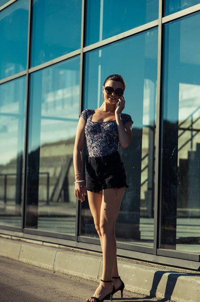 Beautiful girl in short shorts near the shop window. - Foto, imagen