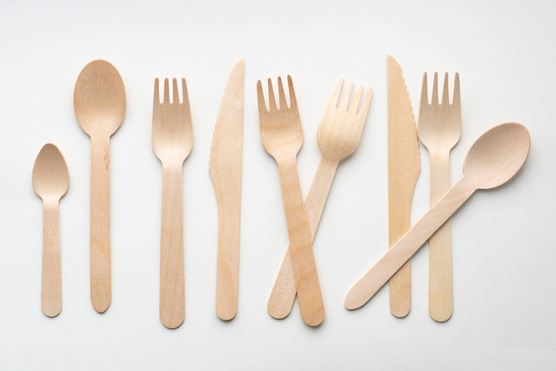 Shot of wooden eco-friendly cutlery lying in a row on a white background. Ecology concept - Zdjęcie, obraz