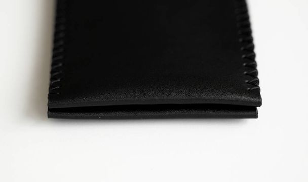 Empty black mens money clip handmade leather wallet with a two pockets for cards lies on a white table. Selective focus, copy space, close up. - Foto, Bild
