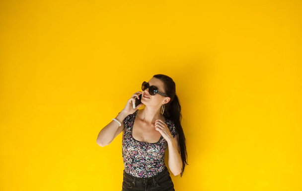 Sexy girl in shorts poses a yellow wall. - Foto, Imagen