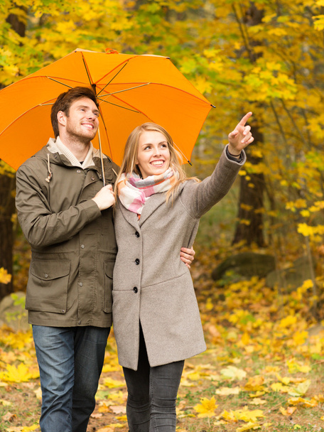 smiling couple with umbrella in autumn park - Foto, afbeelding