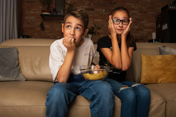 Cute children watching movie on TV on sofa in evening - Photo, Image