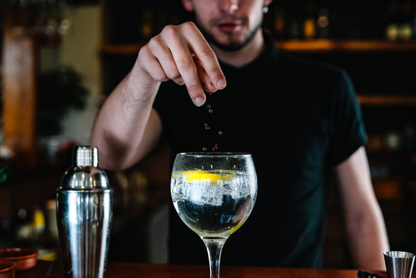 Detalle de un camarero manos añadiendo ingredientes en un vaso de cristal con hielo para bebidas mixtas. Discoteca. - Foto, Imagen