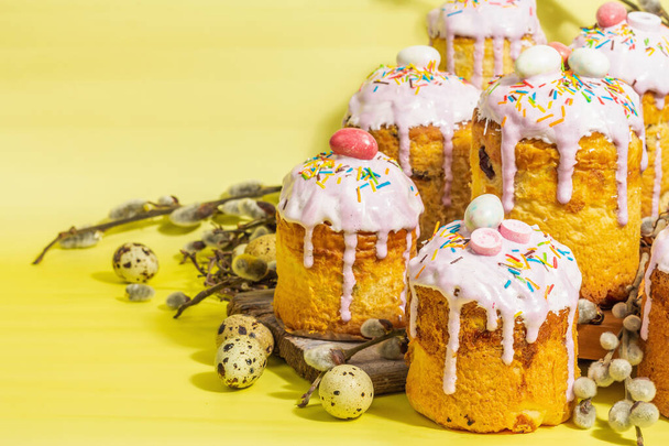 Traditional Easter cake. Festive sweet food with icing and decor. Eggs, nest, willow, trendy hard light, dark shadow. Traditional baking on bright yellow background, copy space - Foto, afbeelding