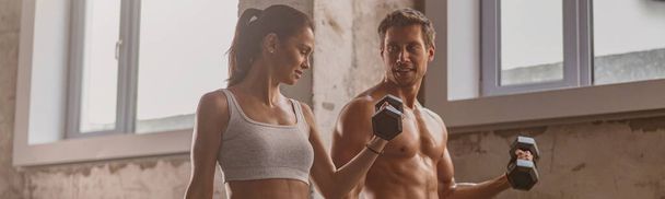 Sporty man in the gym with athletic woman performing sports exercises - Фото, зображення