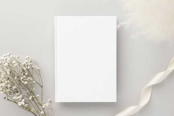Λευκό βιβλίο κενό κάλυμμα mockup σε ένα μπεζ φόντο με ξηρό λουλούδι, επίπεδη lay, mockup - Φωτογραφία, εικόνα