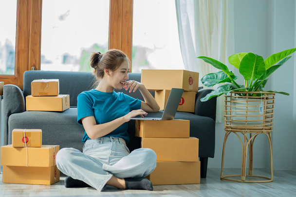 Asian woman working with box and laptop at home at work Starting a small business owner Entrepreneurship, small business, SME or freelance online and delivery ideas. - Foto, imagen